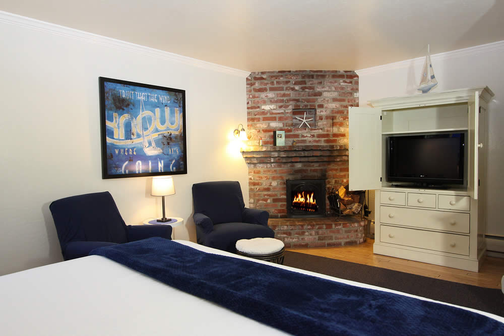 room with bed, chairs and fireplace and TV