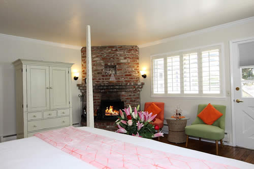 carmel boutique inn guestroom - bed, chairs and table, fireplace